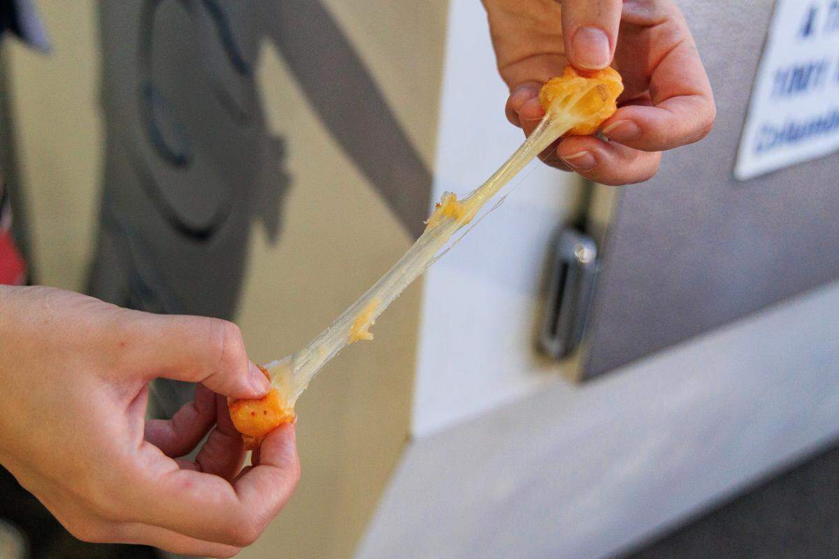 The State reporter Morgan Hughes checks the stretchiness of a cheese curd during the opening day of the South Carolina State Fair on Wednesday, October 11, 2023.