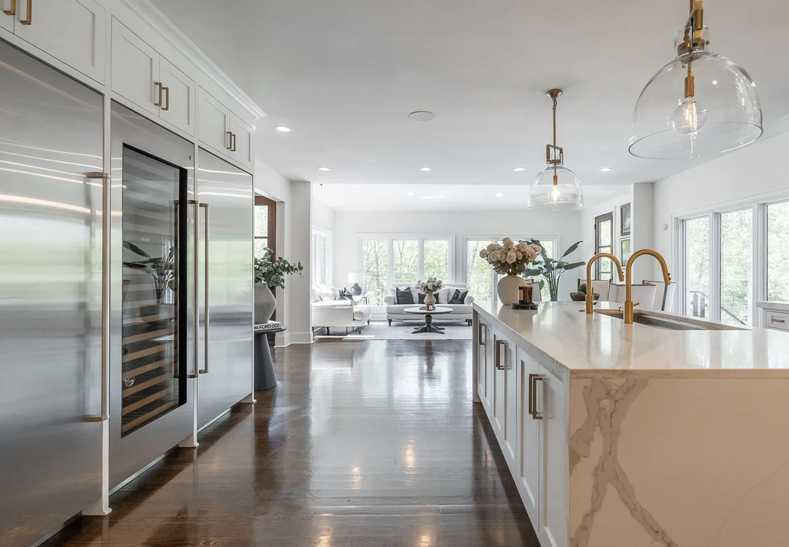 The kitchen includes Wolf double ovens, a six-burner gas range with Coppersmith hood, Subzero refrigeration, and two-inch-thick quartz countertops. A large island has a double sink, Cove dishwasher, and storage. There is also a coffee bar.