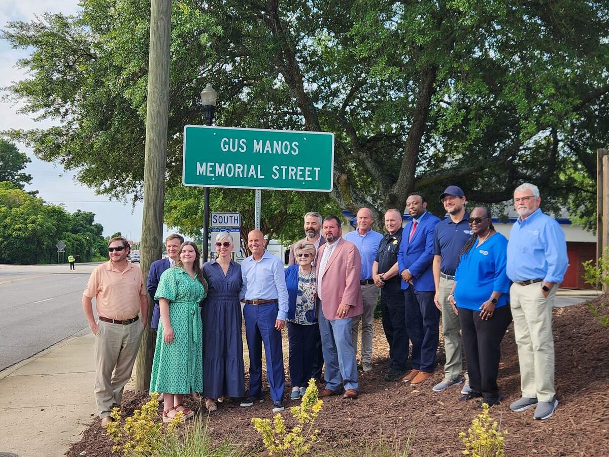 Family members, elected officials and others gather on July 1, 2026, for the unveiling of a sign noting a section of 12th Street in West Columbia as Gus Manos Memorial Street. Manos, a longtime owner of Zesto of West Columbia, died in 2025.