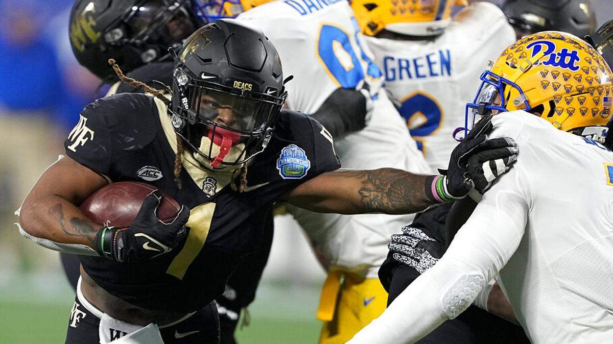 Wake Forest running back Christian Beal-Smith pushes past Pittsburgh linebacker SirVocea Dennis during the first half of the Atlantic Coast Conference championship NCAA college football game Saturday, Dec. 4, 2021, in Charlotte, N.C.