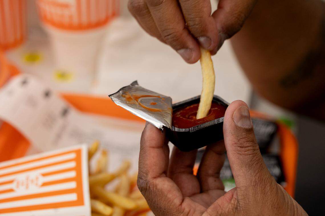 Eric Parker dips his fries in spicy ketchup while dining during the grand opening of the Whataburger in Irmo on Monday, Sept. 9, 2024.