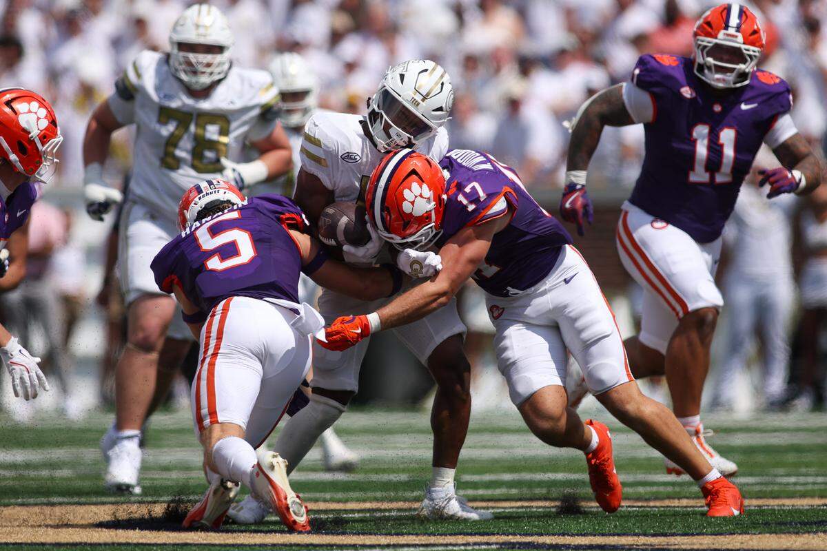 Georgia Tech Yellow Jackets running back Malachi Hosley (0) is tackled by Clemson Tigers defensive back Ronan Hanafin (5) and linebacker Wade Woodaz (17) in the second quarter at Bobby Dodd Stadium at Hyundai Field.