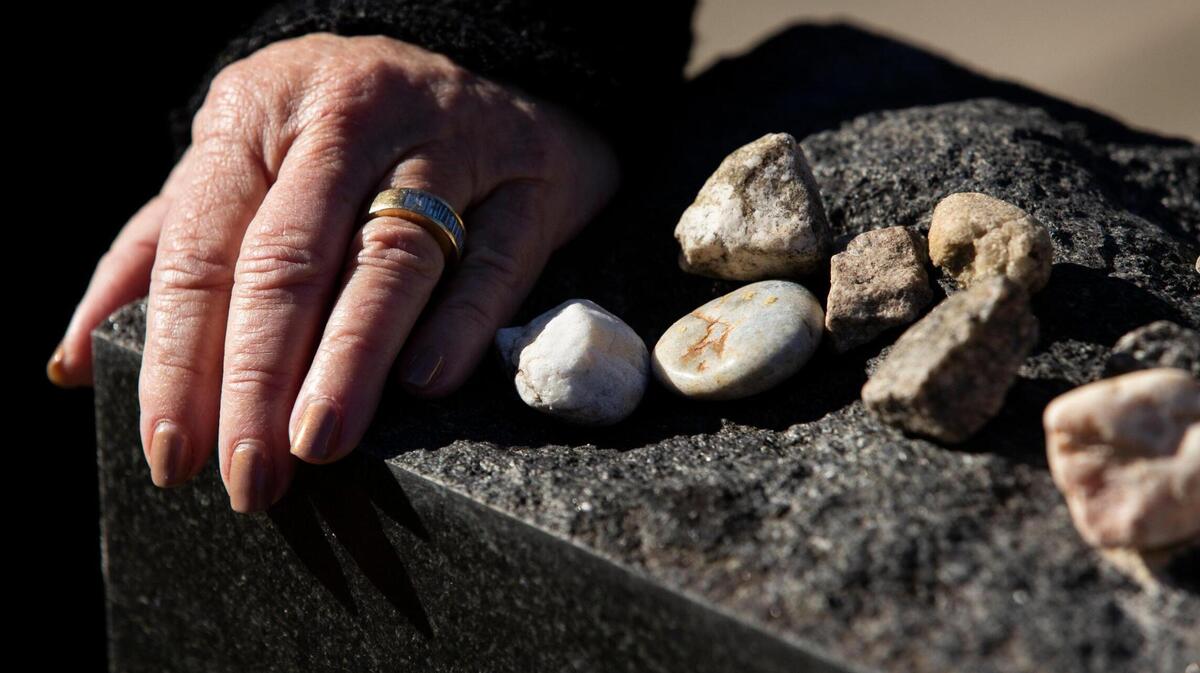 Dr. Lilly Filler rests her hand on a memorial for victims of the Holocaust and Filler’s family who survived the Holocaust at Beth Shalom Cemetery on Thursday, December 10, 2020. She and her siblings placed the gravestone to honor all of their family members they never had the chance to meet because of their deaths in the Holocaust.