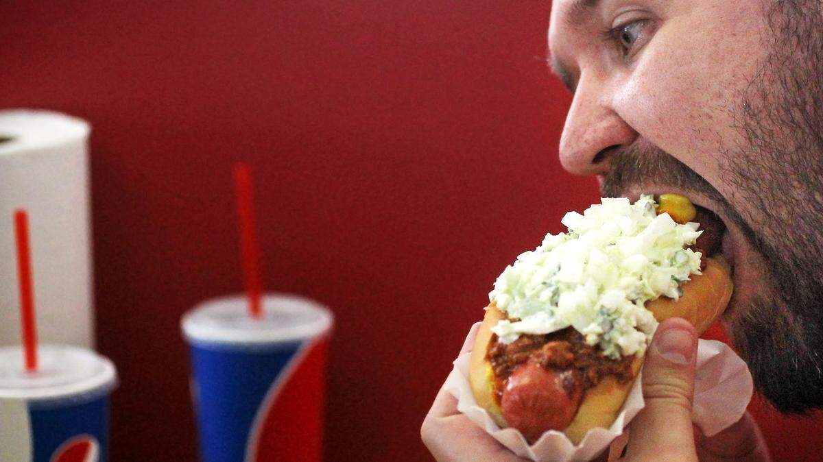 Adam Fischer enjoys one of Sandy’s Famous Hot Dogs at their Main Street location, Friday, March 11, 2016.