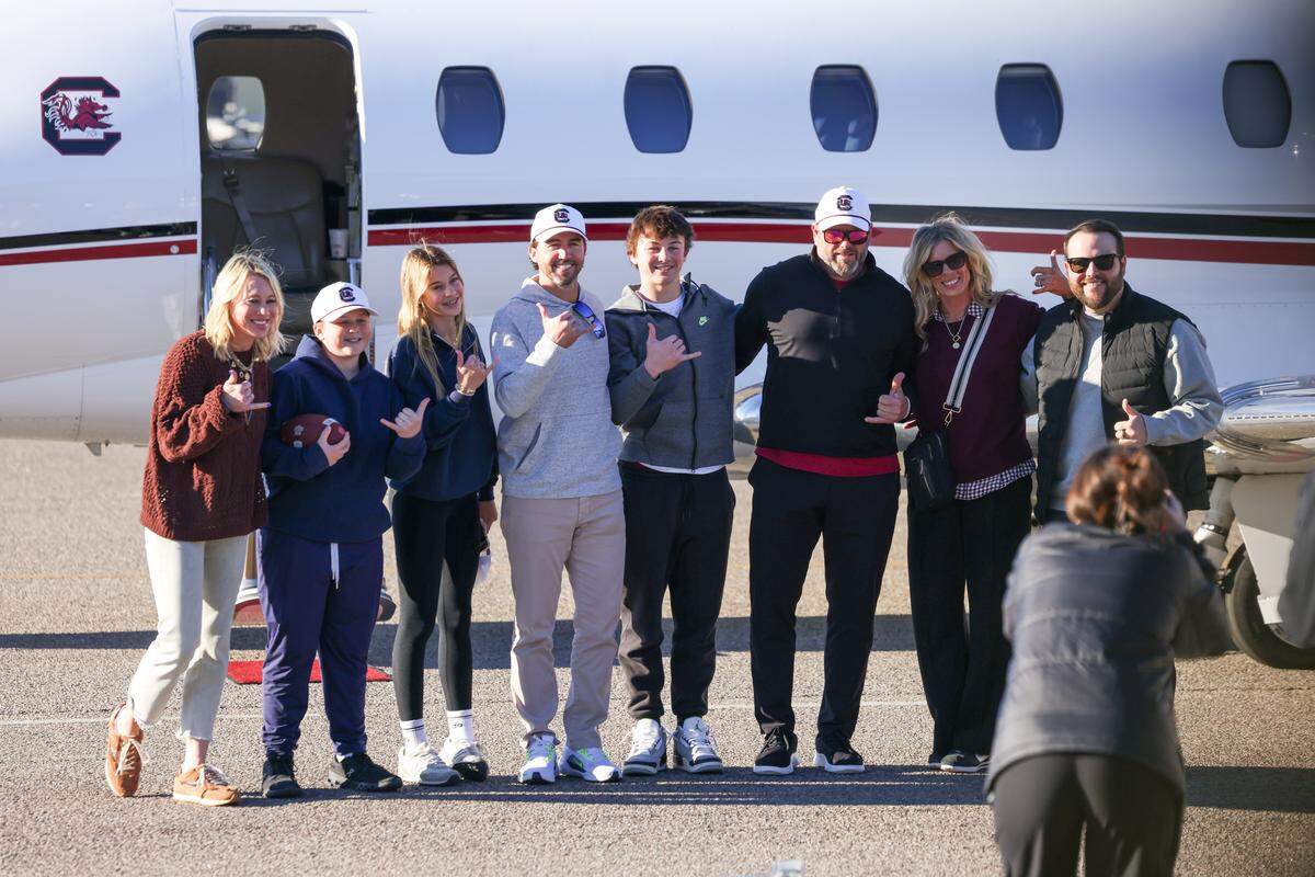 New South Carolina offensive coordinator Kendall Briles and new offensive line coach Randy Clements stand with their families after arriving at Jim Hamilton-LB Owens Airport in Columbia on Thursday, December 11, 2025.