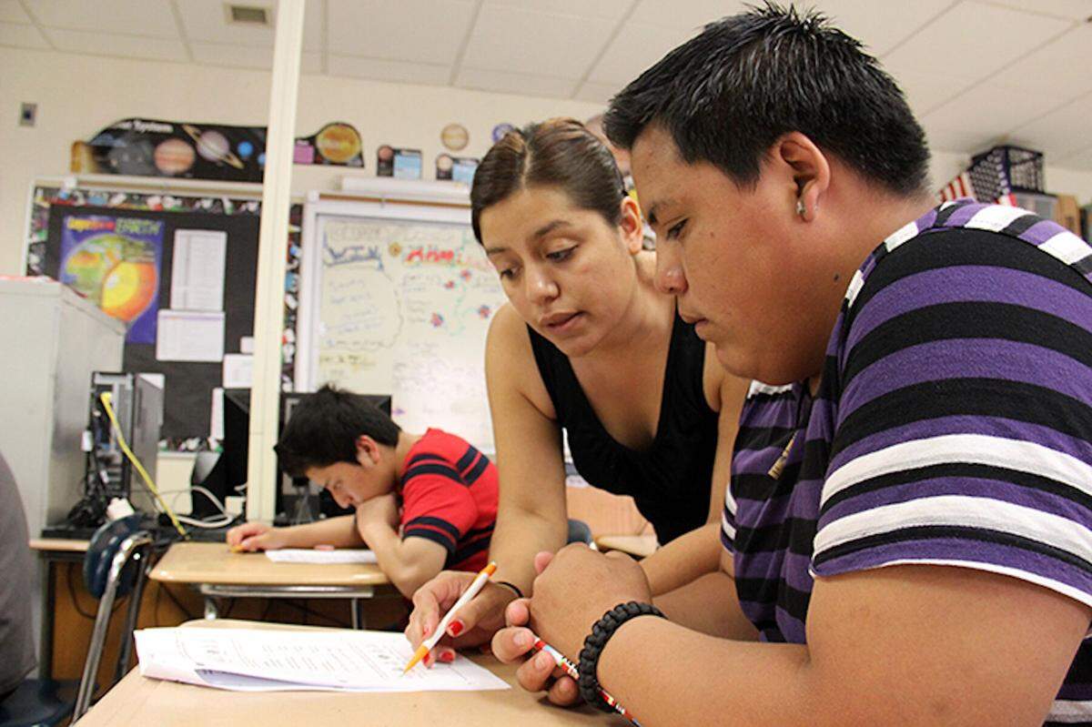 A high school teacher in New York helps a student during class. Due to its highly interpersonal nature, high school teaching ranks very low on the automation-risk scale.