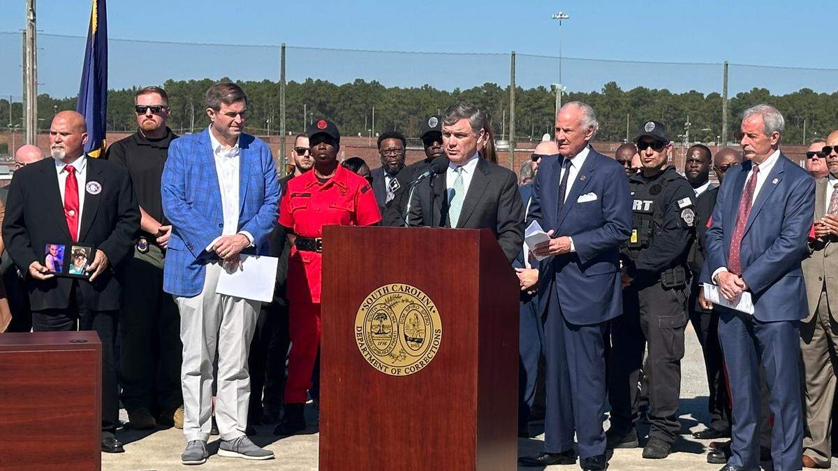 Bryan Stirling, with Gov. Henry McMaster to his left, speaks to reporters at an undated press conference at the main campus of the S.C. Department of Corrections outside Columbia.