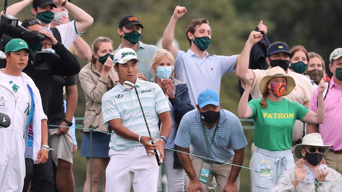 Spectators react as Hideki Matsuyama chips it close to the cup from the gallery to save par and finish in the lead at 11 under par during the third round of the Masters golf tournament at Augusta National, Saturday, April 10, 2021, in Augusta, Ga. (Curtis Compton/Atlanta Journal-Constitution via AP)
