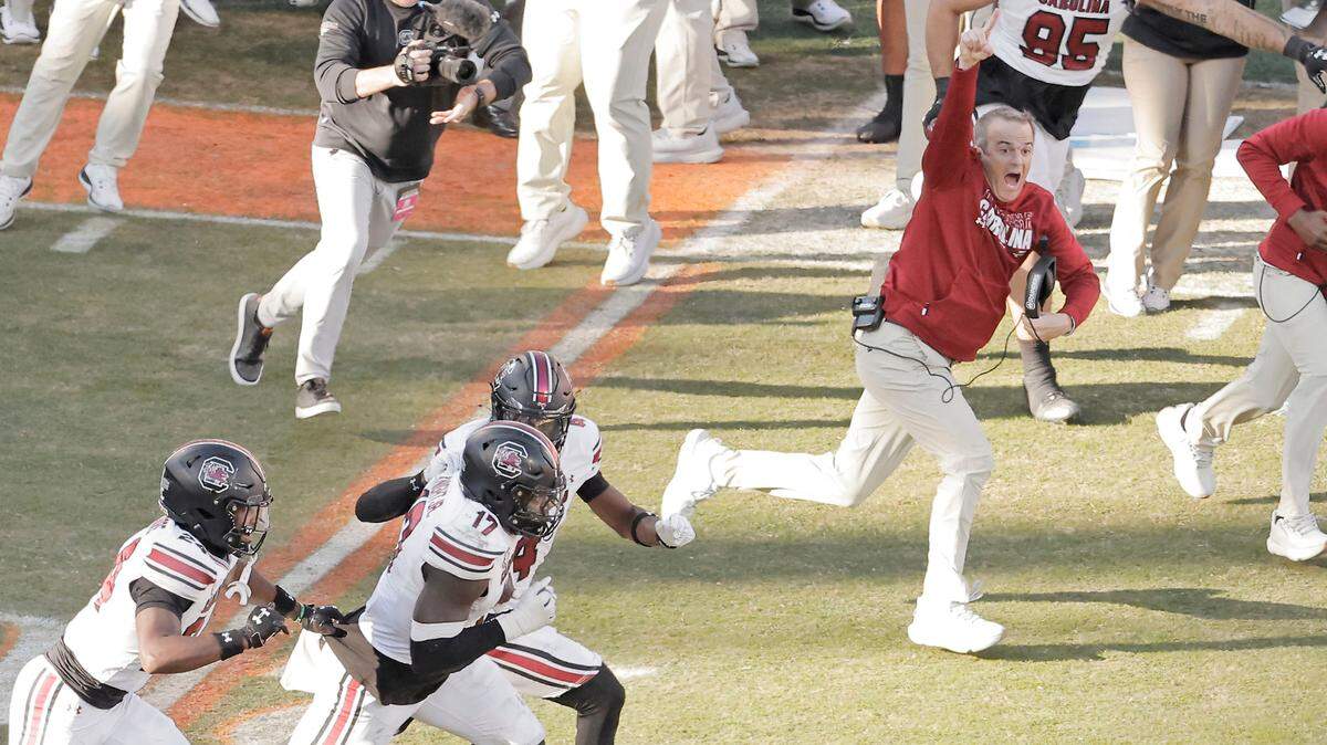 South Carolina head coach Shane Beamer runs alongside his team as South Carolina linebacker Demetrius Knight Jr. (17) celebrates his interception during second-half action in Clemson, S.C. on Saturday, Nov. 30, 2024.