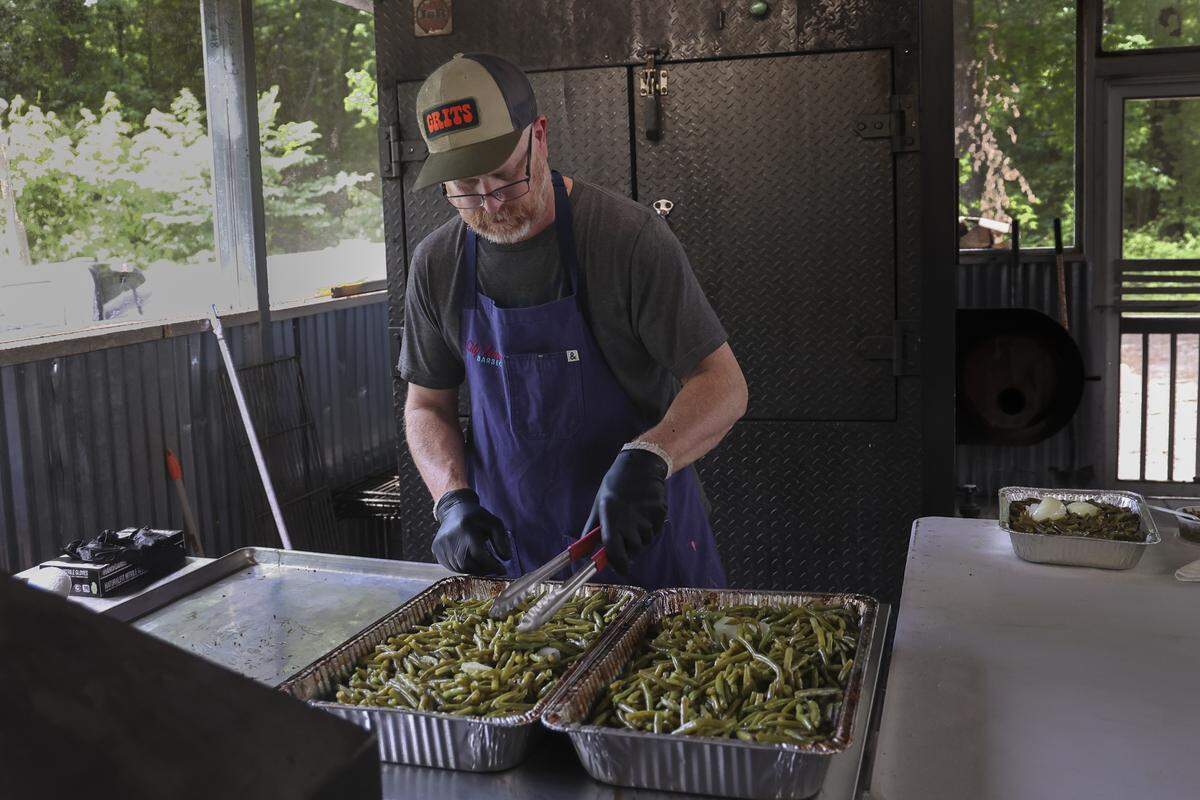 Robbie Robinson prepares green beans at his City Limits Barbeque restaurant in West Columbia. Robinson braises the fresh beans in the smoker, underneath the dripping pork belly. 