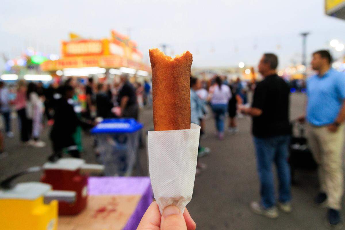 The State photojournalist Joshua Boucher shows a Pronto Pup during the opening day of the South Carolina State Fair on Wednesday, October 11, 2023. Pronto Pups are made with pancake batter instead of a cornmeal batter that more common corndogs use.