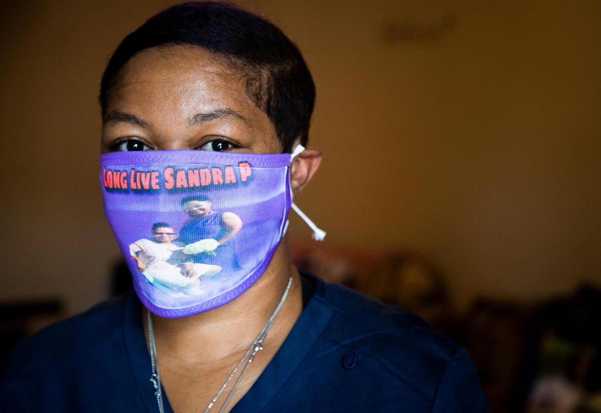 Crystal Priester wears a mask with a picture of herself and her mother Sandra Priester at her home on Saturday, June 27, 2020. Sandra died of the coronavirus in March.
