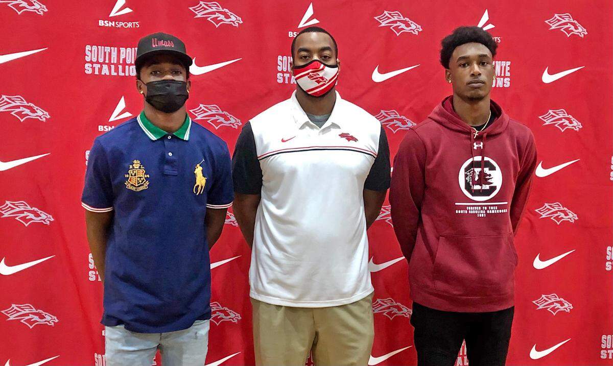 South Pointe High School football coach Devonte Holloman on Wednesday with Jordan Mahoney (left, UMass signee) and Omega Blake (right, South Carolina signee).