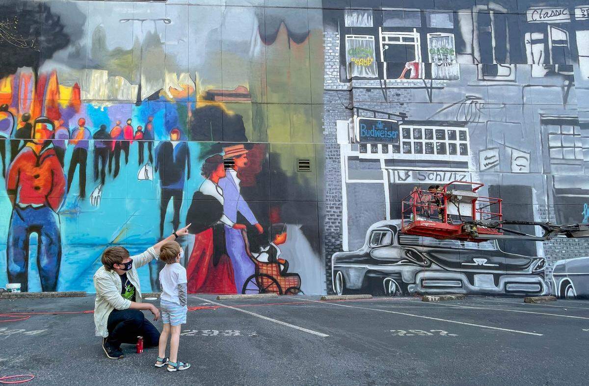 Paul Lindley and his son, Ezra Lindley, 5, look at the mural that artist Ija Charles is painting at 1401 Main Street  4/6/21