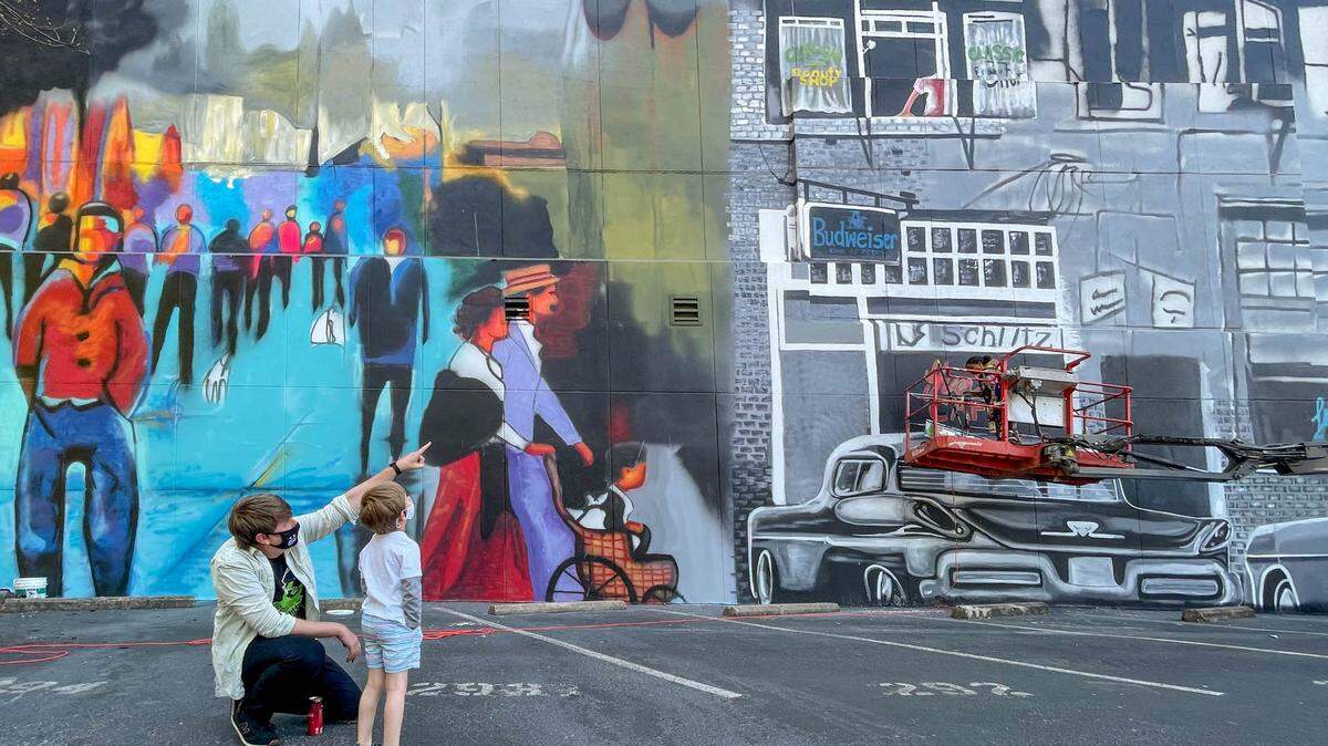 Paul Lindley and his son, Ezra Lindley, 5, look at the mural that artist Ija Charles is painting at 1401 Main Street 4/6/21