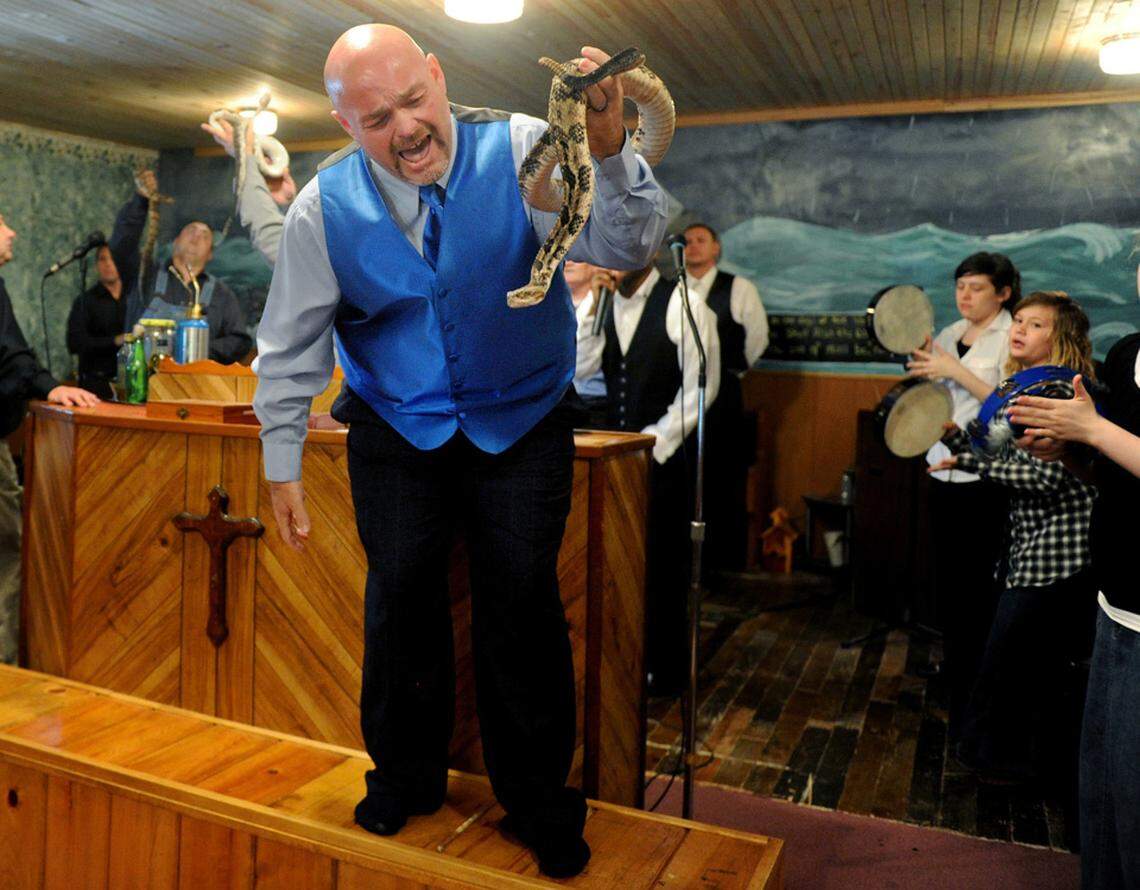 Jamie Coots, pastor of the Full Gospel Tabernacle in Jesus Name Church of Middlesboro, Ky, stands on a bench before the church, singing and holding a rattlesnake during service at Tabernacle Church of God in LaFollette, Tenn.  on May 6, 2012.