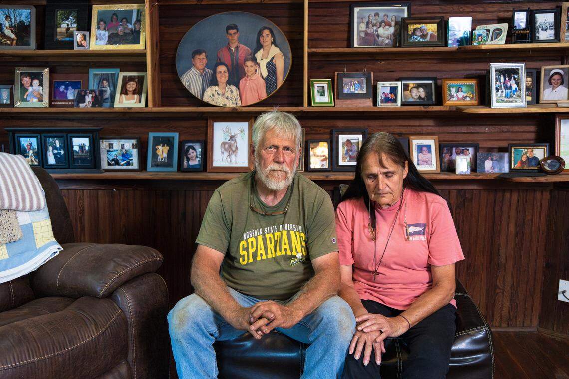 Willy and Lucy Case sit before a wall of family photos inside their home.