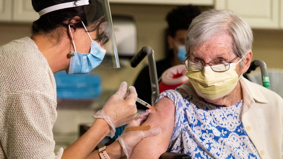 Nora Schafer receives the first shot of the coronavirus vaccine from Dr. Jennifer Henzler at Wellmore of Lexington on Wednesday, December 30, 2020. Schafer is looking forward to seeing her son after she is fulling vaccinated.