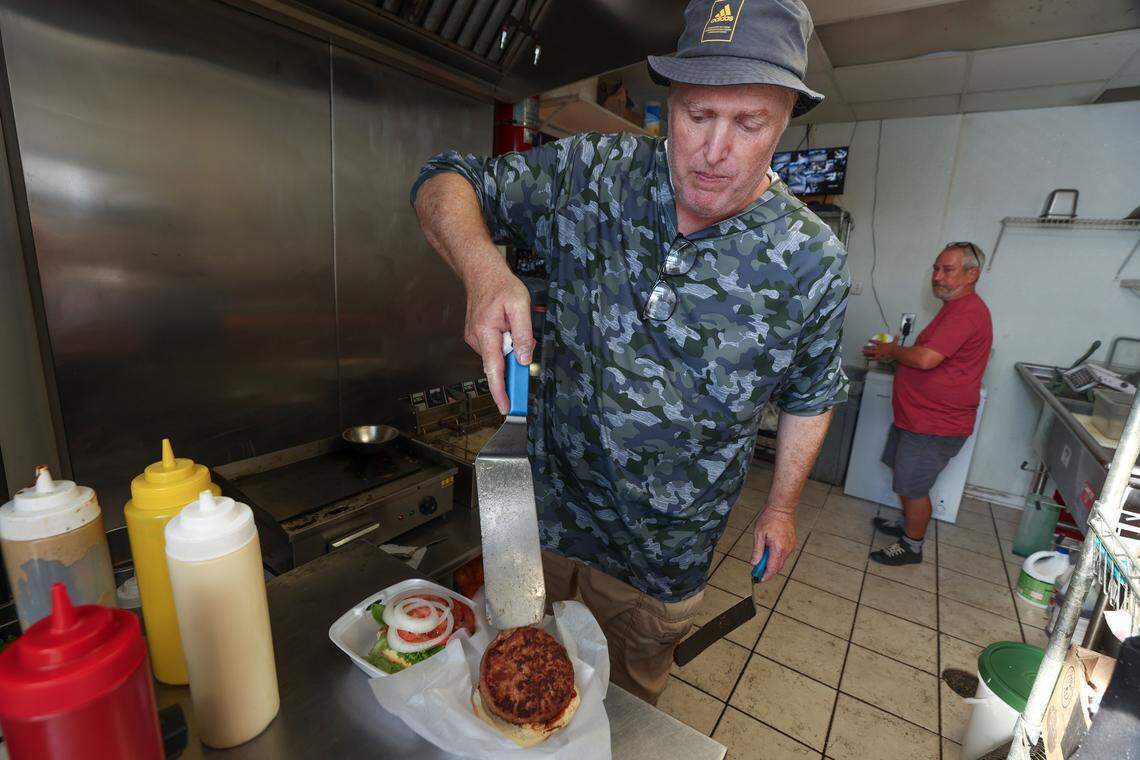 Dirk Sobotka, with Kipp Shives in the background, prepares an order for a food delivery service at the Granby Burger kitchen inside Lucky’s in Five Points on Thursday, August 14, 2025.