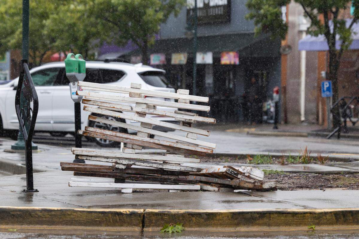 People walk through rain and past a pile of barricades in Five Points before Tropical Storm Debby arrives in Columbia, South Carolina on Tuesday, August 6, 2024.
