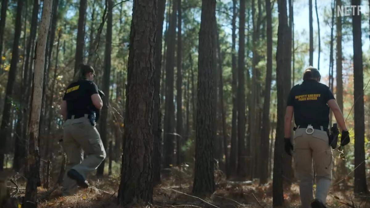 Two sheriff’s deputies search in the woods as part of a missing persons case in a scene from the trailer for a new Netflix crime documentary.