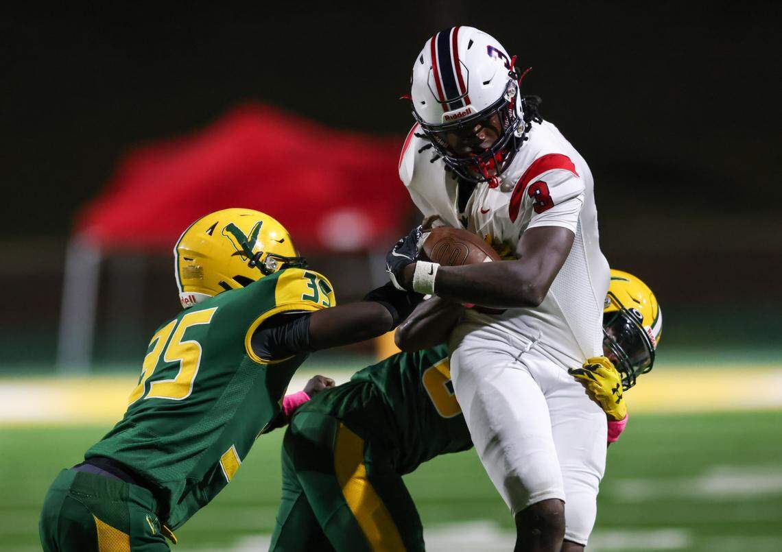 Shamil Saadiq (3) of Lugoff-Elgin fends off the tackle of Daniel Jenkins (35) and Tristian Williams (6) of Spring Valley during Spring Valley’s game against Lugoff-Elgin in Columbia on Oct. 25, 2024.