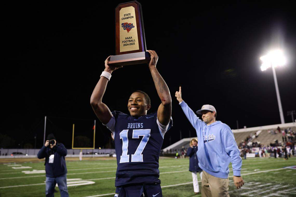 Jayden Sellers (17) of South Florence holds up the trophy following the Class 4A Football State Championships in Orangeburg on Friday, December 13, 2024.