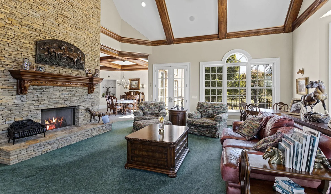 The living room leads to a large patio with an outdoor kitchen, pool and hot tub overlooking a stocked 3.5-acre pond.