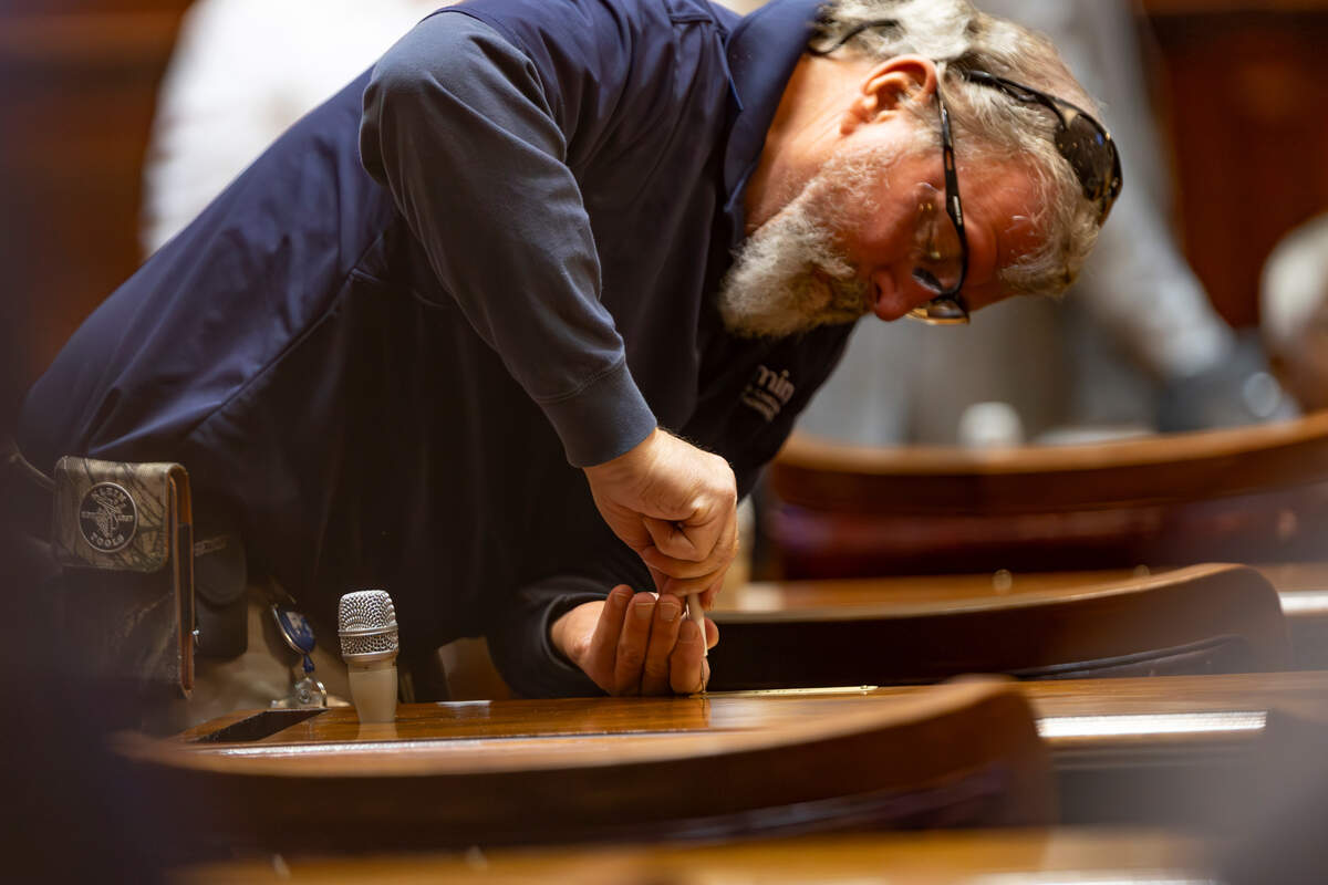 Mark Smith, a facilities maintenance employee, replaces nameplates in the House of Representatives chamber on Tuesday, Dec. 3, 2024. Members of the House met in advance of the 2025 Legislative Session to swear in new members and reassign seats in the chamber.