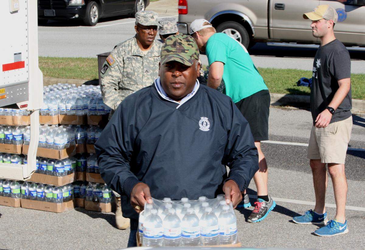 Volunteers, including Columbia Mayor Steven Benjamin, distributed water to people in need at Lower Richland High School on Oct. 6, 2015, after flooding closed roads in the area, making it difficult for people to get food and water.
