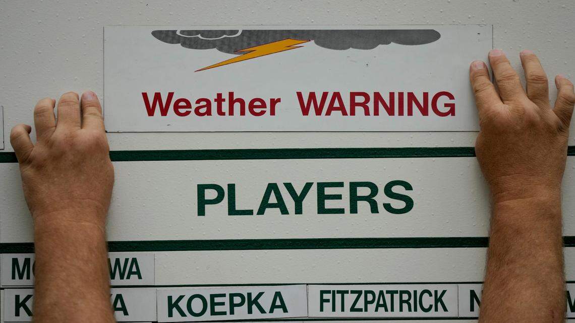 A course worker puts up a weather warning sign on a leader board during a practice round for the Masters golf tournament on Wednesday, April 6, 2022, in Augusta, Ga. (AP Photo/Matt Slocum)