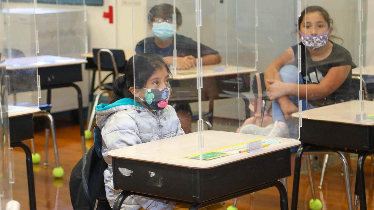 Fourth-graders sit in a classroom on Wednesday, Aug. 18, 2021, the first day of school at A.C. Moore Elementary School. Social distancing, masks and plexiglass dividers help prevent the spread of the coronavirus.