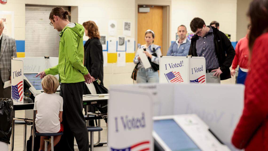 Ellis RIkard, 9, patiently waits as his dad, Jason Rikard, casts his ballot at Hand Middle School on Tuesday, Nov. 5, 2024.
