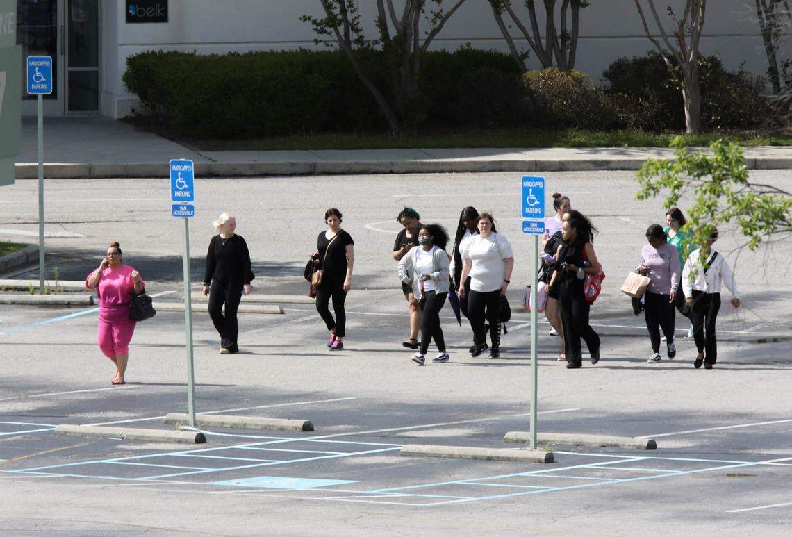 People who were inside the Columbiana Centre mall when a shooting occurred walk through the parking lot on Saturday, April, 16, 2022.