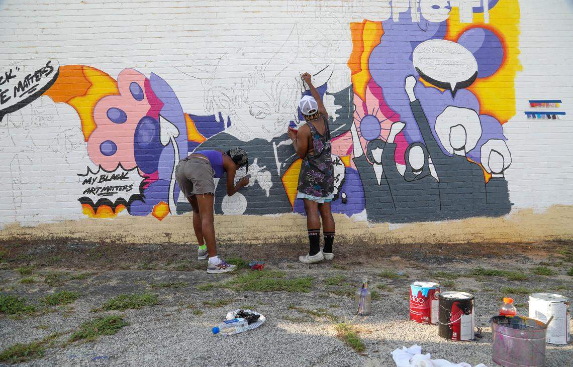 Artists Ariel Flowers and Robb Kershaw paint a mural on the side of Sweet Temptations Bakery at 2231 Main St. Jared Johnson had wanted to follow many other cities and paint a Black Lives Matter Mural on a street in Columbia after the death of George Floyd. He ended up moving the project to the side of the building when proposals to paint on the street were not approved.