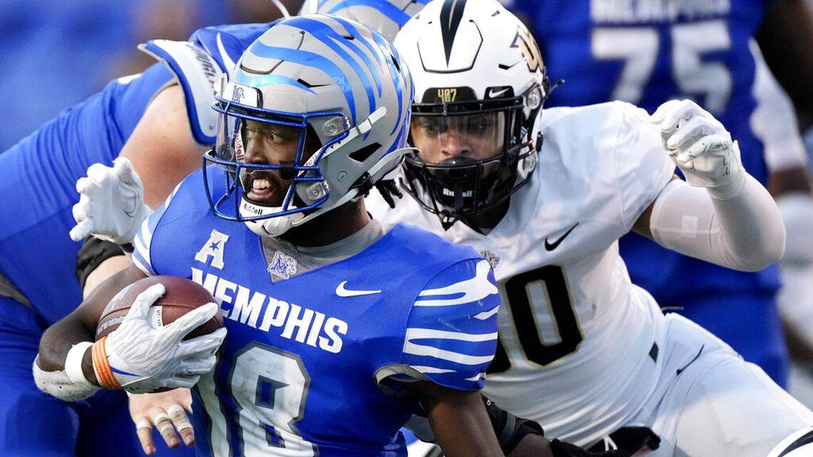 Memphis wide receiver Eddie Lewis (18) carries the ball as Central Florida linebacker Kam Moore, right, closes in during the second half of an NCAA college football game Saturday, Nov. 5, 2022, in Memphis, Tenn.