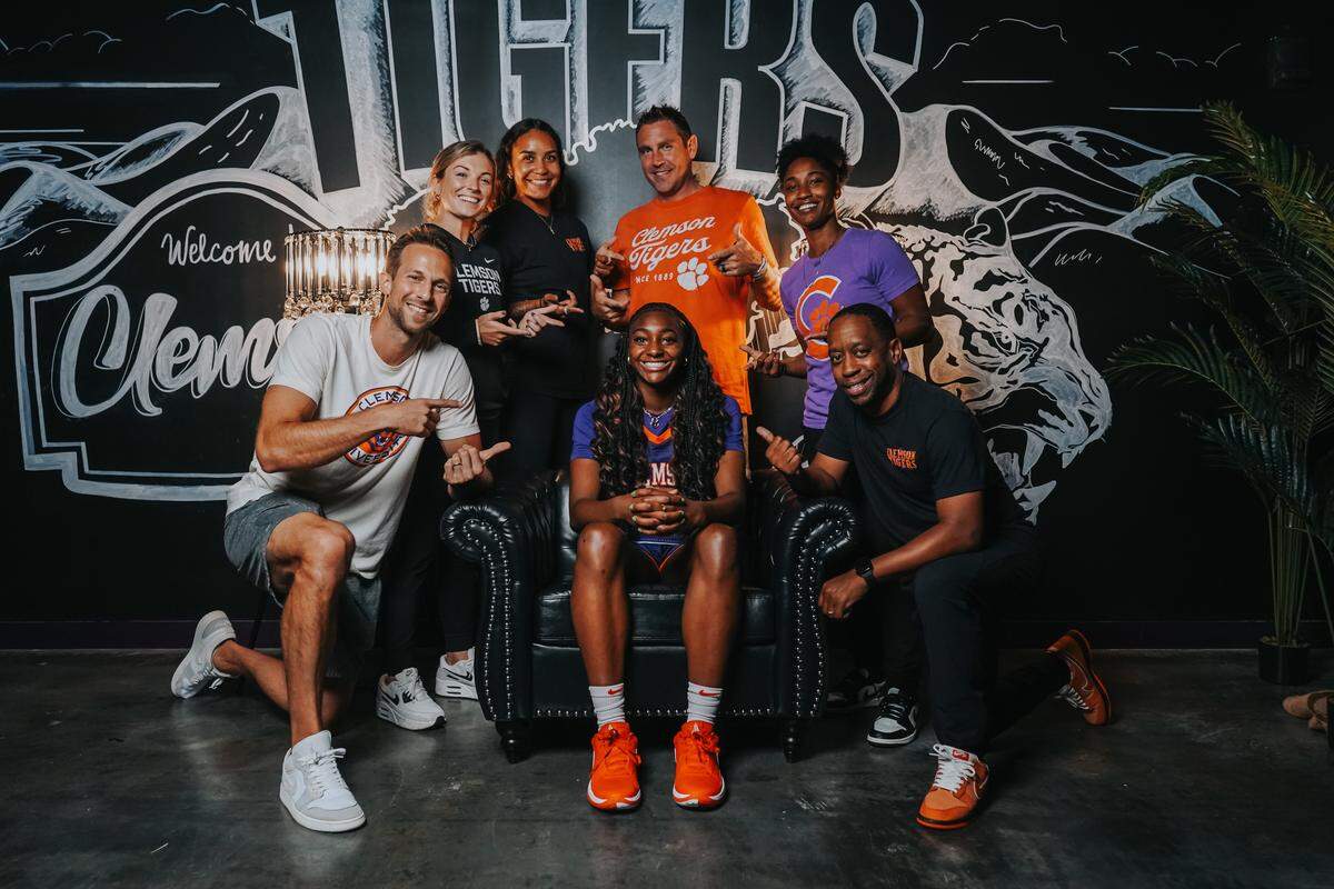 Five-star 2026 recruit Trinity Jones (middle) poses with the Clemson women’s basketball coaching staff including head coach Shawn Poppie (standing in orange T-shirt) during her official visit to campus. Jones’ mother said Clemson associate head coach Chris Ayers (kneeling to the right of Jones) played a key role in the recruiting process.