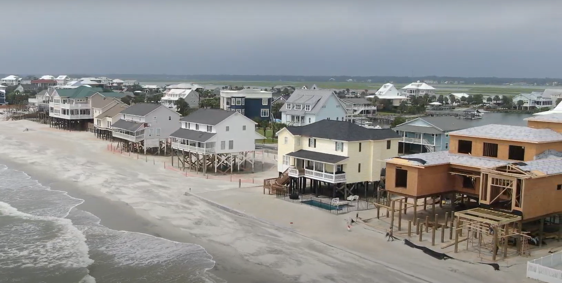 Two houses in the left of this photograph at Garden City, S.C., are not protected by a seawall and have been undermined by the ocean. A home to the right is protected by a seawall, as is a home under construction. (Photo from August 2024)