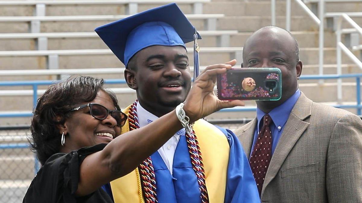 Airport High School graduate Marcus Gadsden gets his picture taken with his parents, Yvonne and Richard Gadsden. Students at the Columbia, S.C. high school were filmed this week as they walked across the stage in an empty stadium. The footage will be combined with speeches and music to create a virtual graduation. 