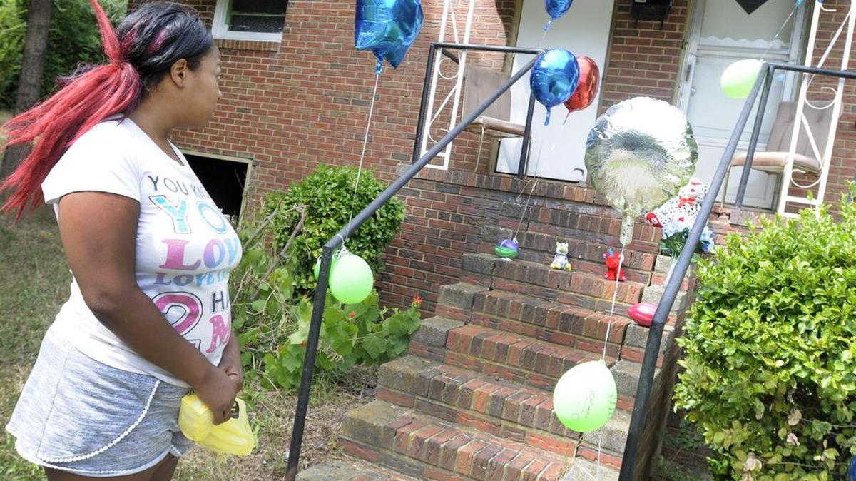 Dolores Hagins looks at a makeshift memorial where 2-year-old Jacarion Gladden died from a gunshot wound.
