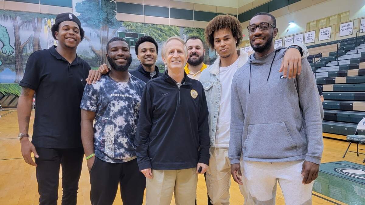 Irmo boys basketball coach Tim Whipple, center, poses for a picture with former players after a win Wednesday in the Chick-fil-A Classic at River Bluff High School.