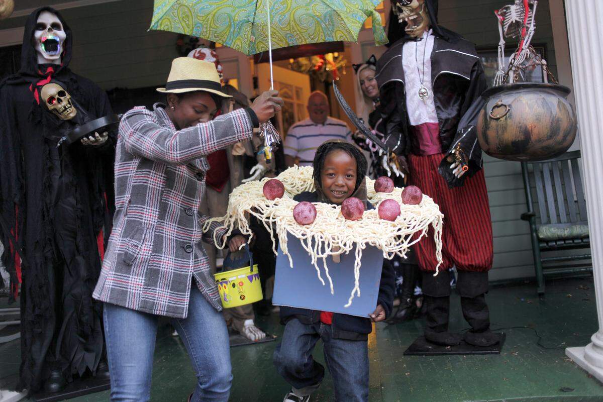 Danielle Fasion holds an umbrella for Azure Fasion, 6, as they trick or treat Halloween night, Monday October 31, 2011 at the home of Jesse Jones at the corner of Oakwood and East Streets in Raleigh. Wake County school administrators are proposing not scheduling classes the day after Halloween for most students in 2023.
