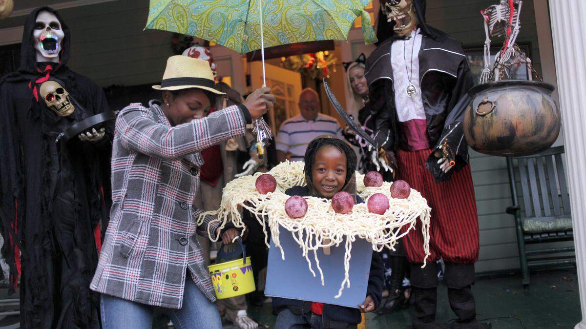Danielle Fasion holds an umbrella for Azure Fasion, 6, as they trick or treat Halloween night, Monday October 31, 2011 at the home of Jesse Jones at the corner of Oakwood and East Streets in Raleigh. Wake County school administrators are proposing not scheduling classes the day after Halloween for most students in 2023.