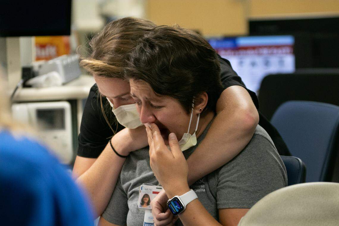 After completing a phone call to a patient’s wife, telling her she needs to come to the hospital because her husband is actively dying, MICU nurse Andrea Crain cries at the nurse’s station as patient care technician Kelly Burchette comforts her. “Everybody is dying and it just makes me so sad,” she said.