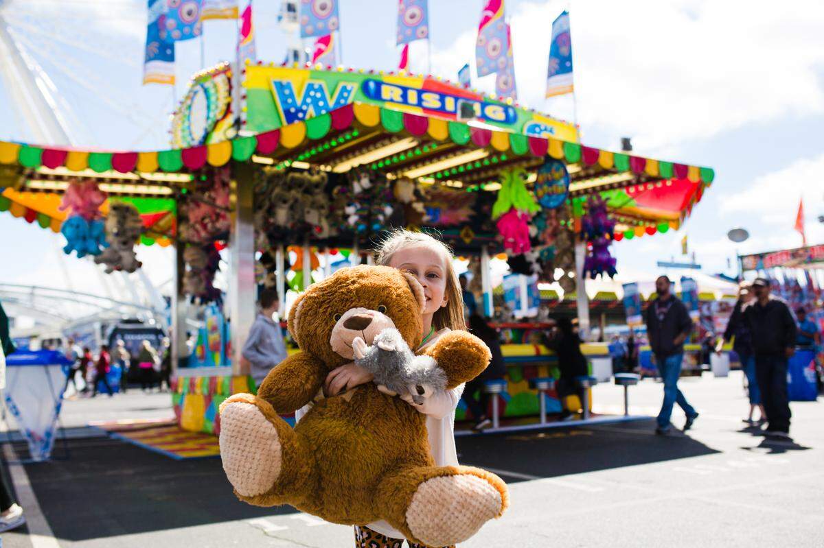 A young girl holds a prize teddy bear at the South Carolina State Fair.