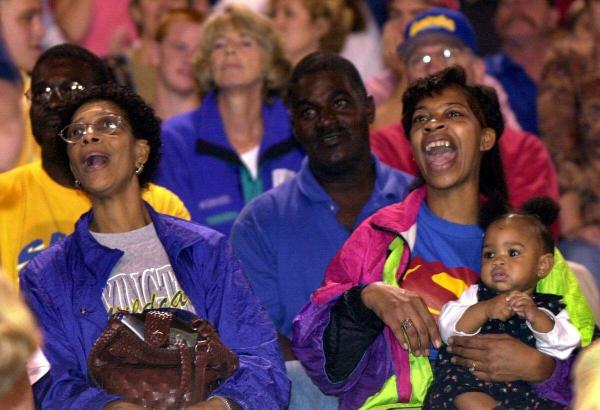 In a photograph from 2002, Jacqueline Summers, right, holds Demetris Summers’ year-old daughter Ny’Asia in the stands at a Lexington High football game. At left is his grandmother Marelda Summers.