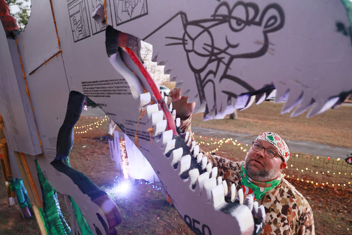 Christopher Price shows dinosaurs he made out of insulation foam outside his home on Wednesday, December 11, 2024. The dinosaurs are visible from Augusta Road in Lexington, South Carolina
