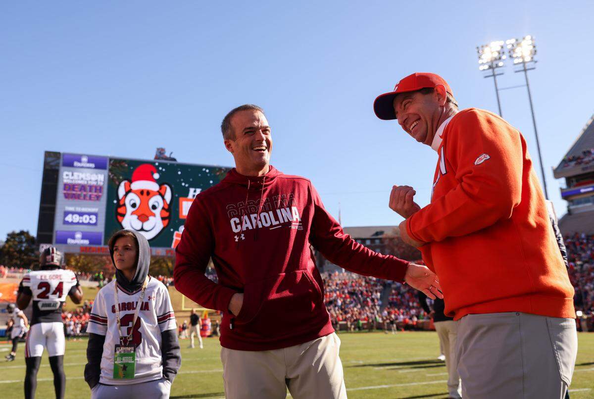 South Carolina head coach Shane Beamer laughs with Clemson head coach Dabo Swinney on the field before the Palmetto Bowl between at Memorial Stadium in Clemson on Saturday, November 30, 2024.