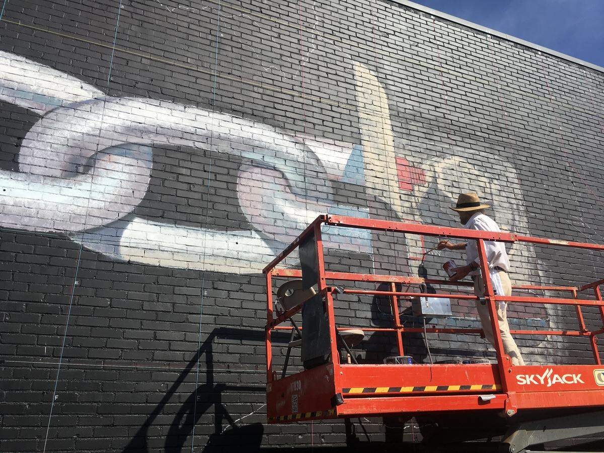 Artist Blue Sky works on a new mural in Five Points.