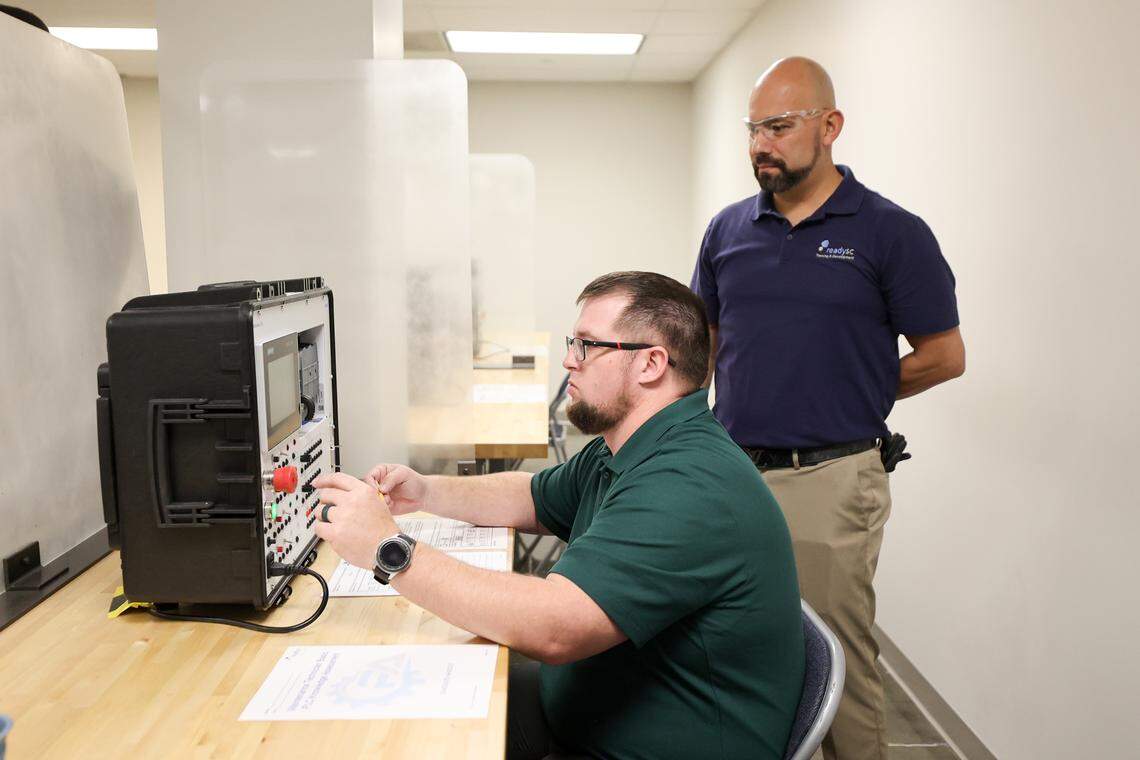 ReadySC instructors Roger Osorio, standing, and Billy McLendon  demonstrate the use of a programable logic control unit in the new training area at the Cornerstone Economic Development and Workforce Training Center at Midlands Technical College. The center is being used to screen applicants for Scout Motors.